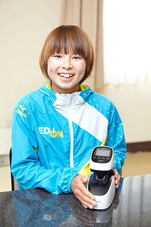 ヘモグロビン測定装置を手にする、女子陸上長距離選手 エディオン女子陸上競技部 「渡邊裕子」さん